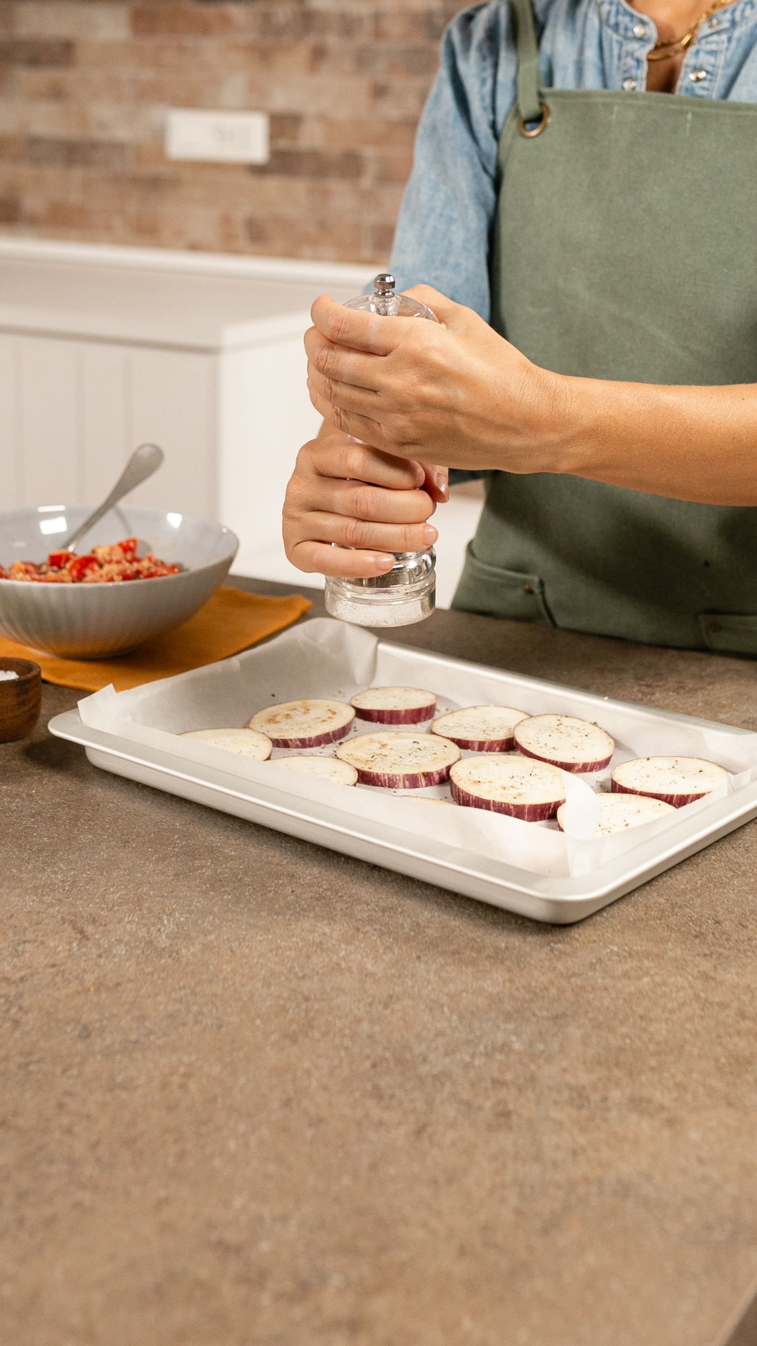 Disponi le fette una accanto all’altra su una teglia foderata con carta forno e condisci con sale e pepe.
